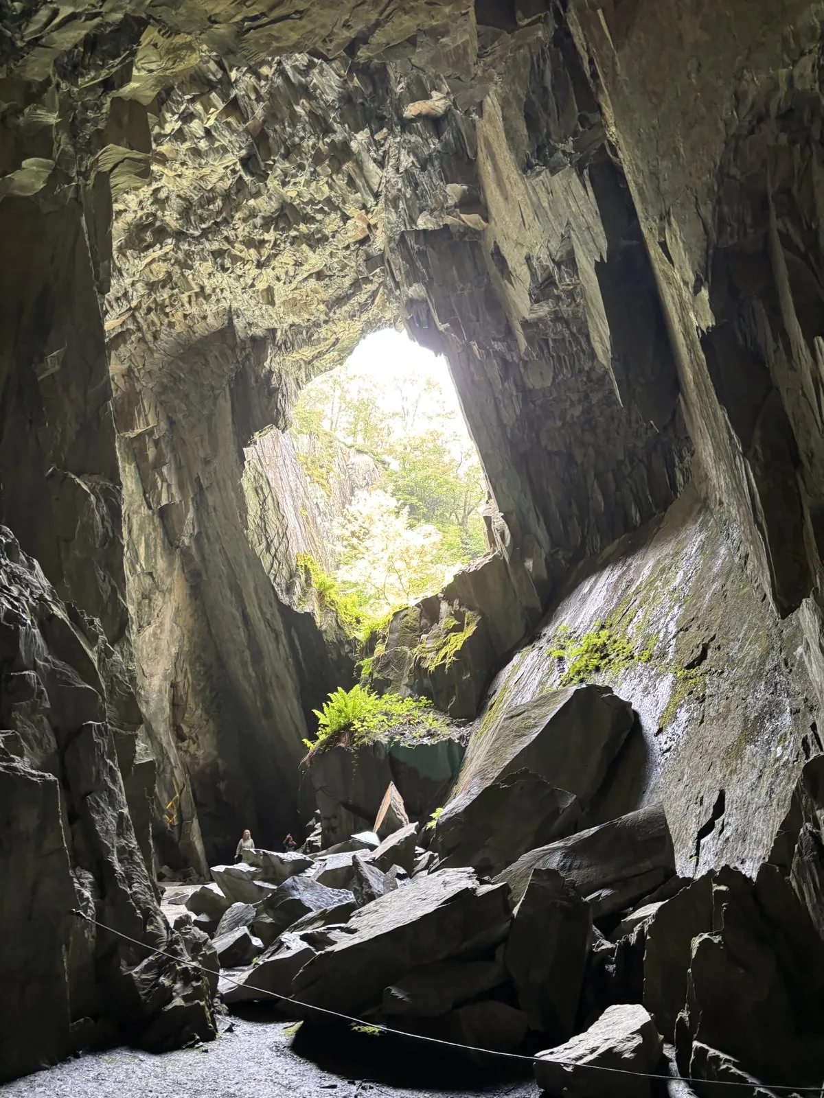 Interior view of a rock cavern with natural light pouring through an overhead opening.